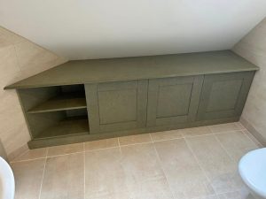 Storage that disappears into the room. This bespoke under-eaves unit was designed to maximise every inch of unused space, with a seamless worktop, shaker-style fronts and a durable sprayed finish that complements the existing bathroom.
